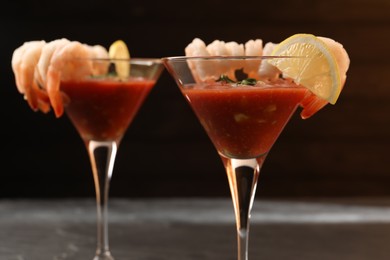 Photo of Tasty shrimp cocktail with sauce in glasses and lemon on grey table, closeup