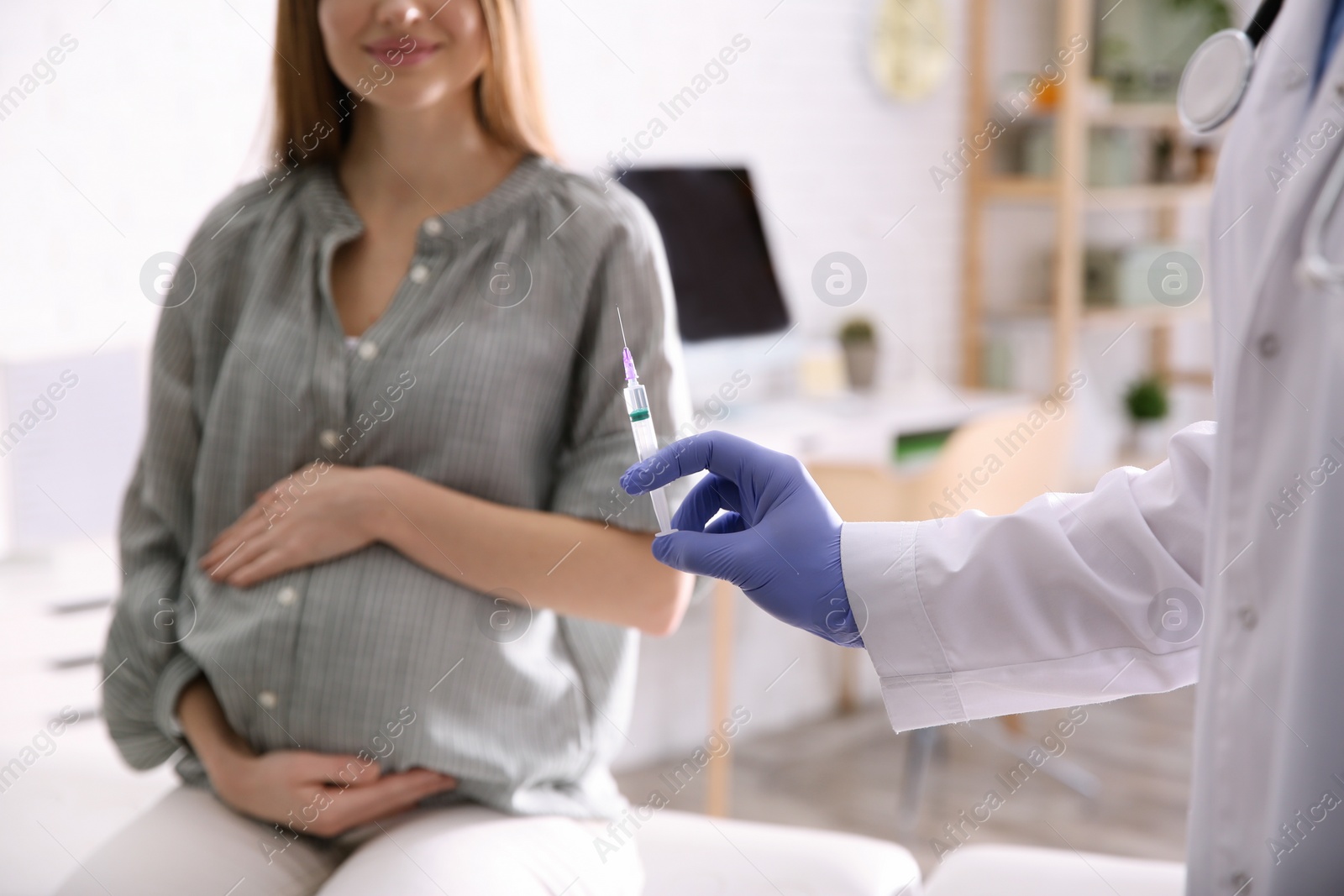 Photo of Doctor giving injection to pregnant woman in hospital, closeup. Vaccination concept