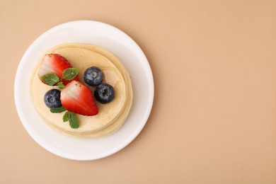 Photo of Stack of tasty pancakes with fresh berries and mint on beige background, top view. Space for text