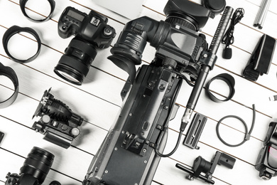 Photo of Flat lay composition with video camera and other equipment on white wooden table