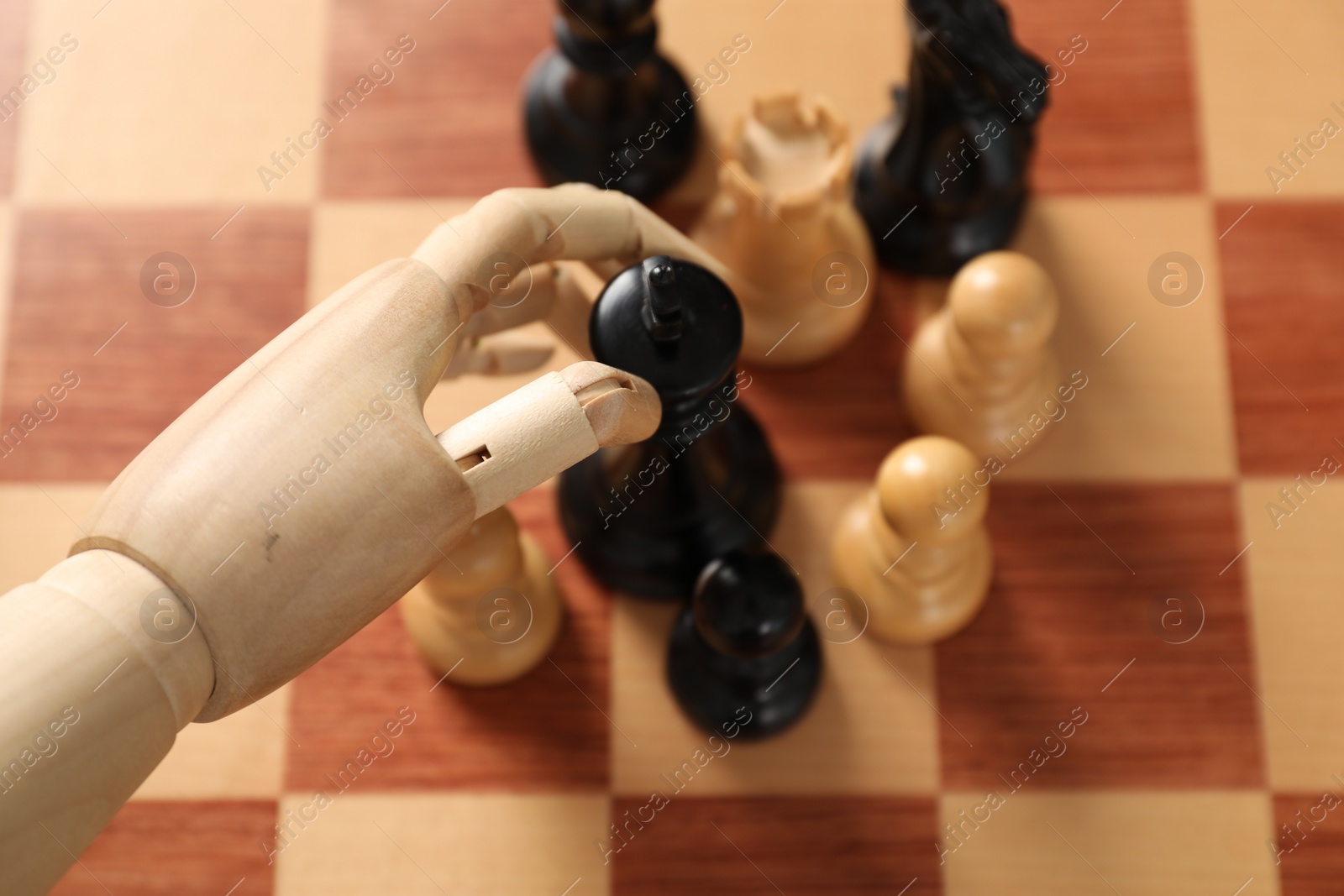 Photo of Robot moving chess piece on board, above view. Wooden hand representing artificial intelligence