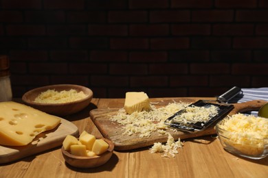 Photo of Different types of cheese and grater on wooden table. Space for text