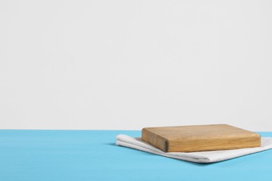 Empty board and towel on light blue wooden table. Space for text