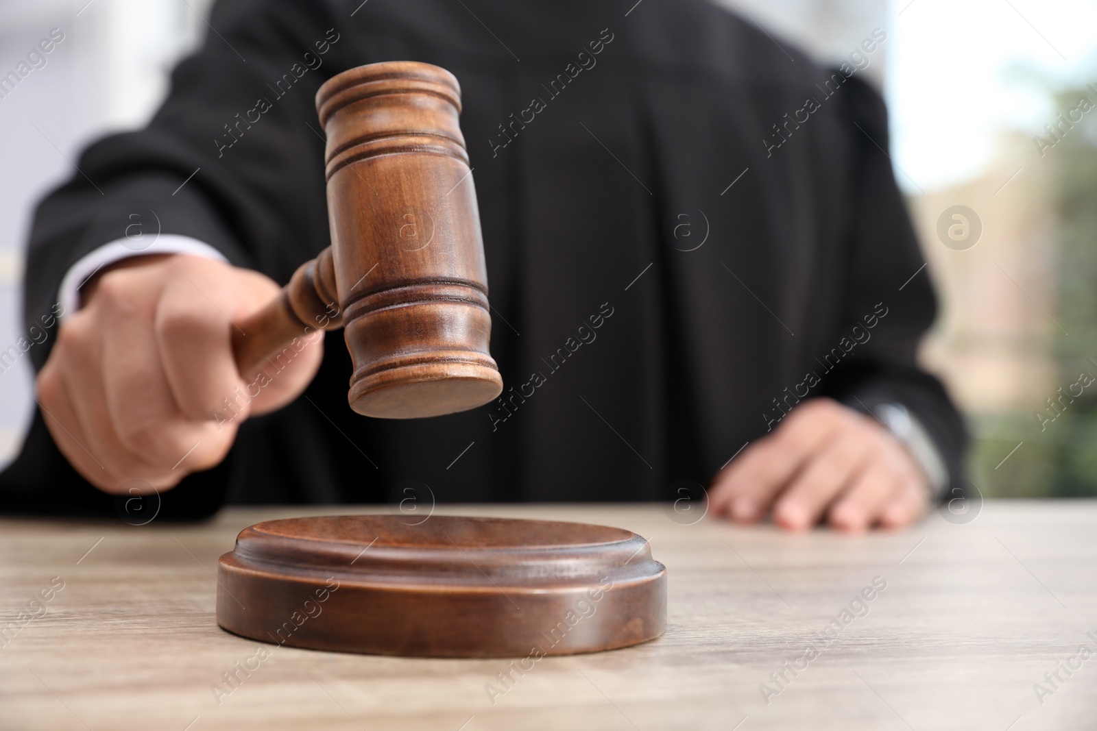 Photo of Judge with gavel at wooden table indoors, closeup. Criminal law