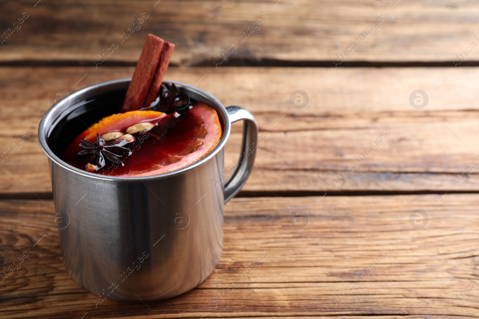 Photo of Aromatic mulled wine on wooden table, space for text