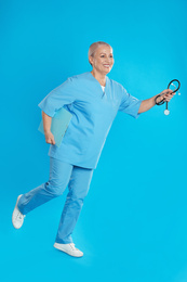 Photo of Mature doctor in uniform running on blue background