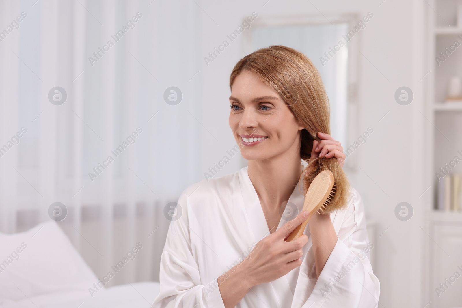 Photo of Beautiful woman brushing her hair in room