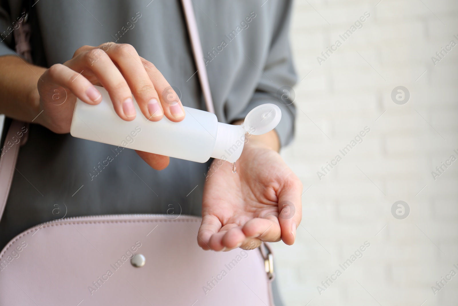 Photo of Woman applying hand sanitizer on light background, closeup. Personal hygiene during COVID-19 pandemic