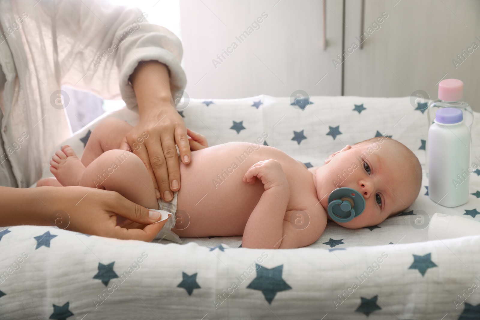 Photo of Mother changing baby's diaper on table indoors, closeup