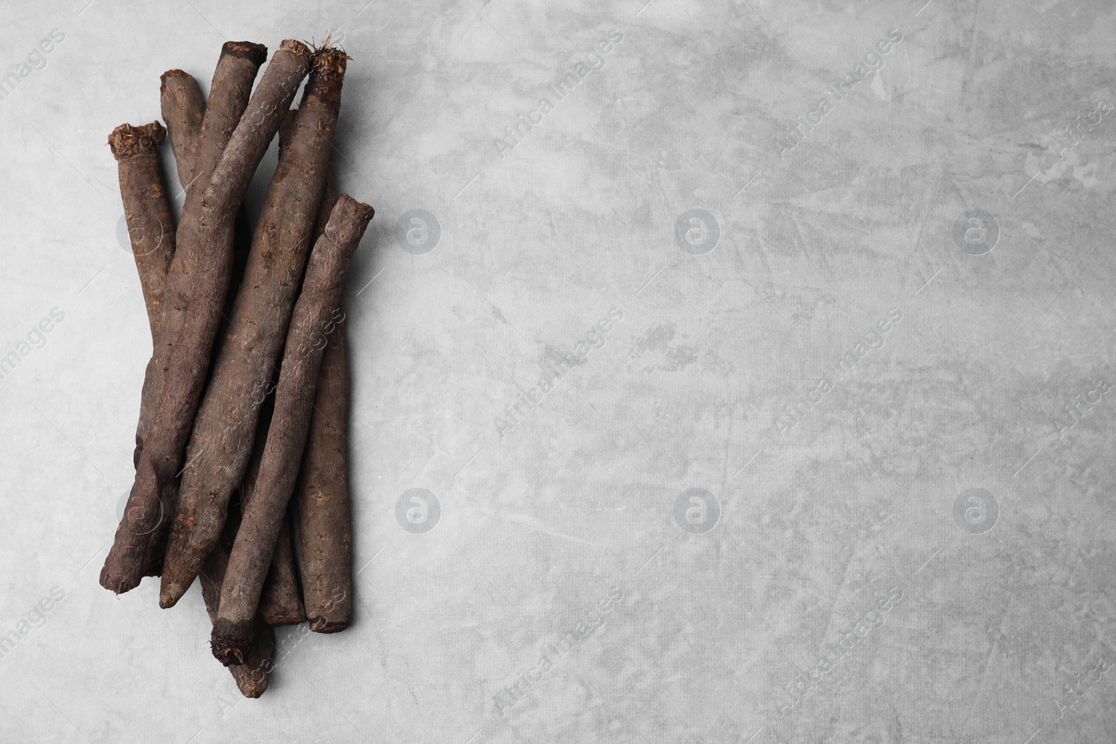 Photo of Raw salsify roots on grey table, flat lay. Space for text