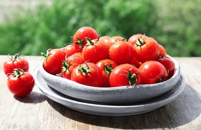 Photo of Plates with fresh ripe tomatoes on table outdoors