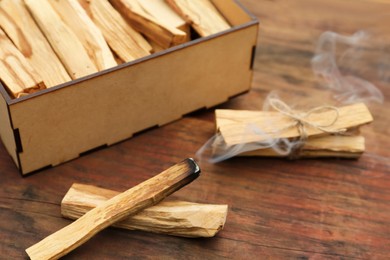 Photo of Many Palo Santo sticks and one smoldering on wooden table