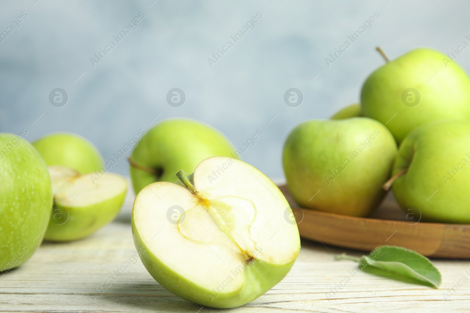 Photo of Fresh ripe green apples on wooden table against blue background, space for text