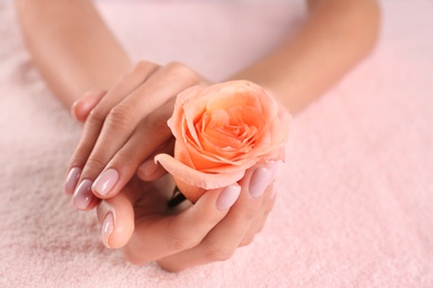 Closeup view of beautiful female hands with rose on towel, space for text. Spa treatment