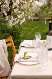 Photo of Stylish table setting with beautiful spring flowers, wine, plates and glasses in garden