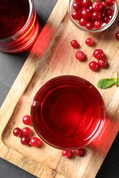 Photo of Tasty refreshing cranberry juice and fresh berries on grey table, top view