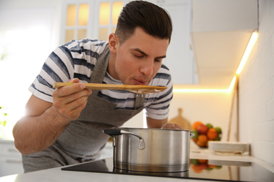 Handsome man cooking on stove in kitchen