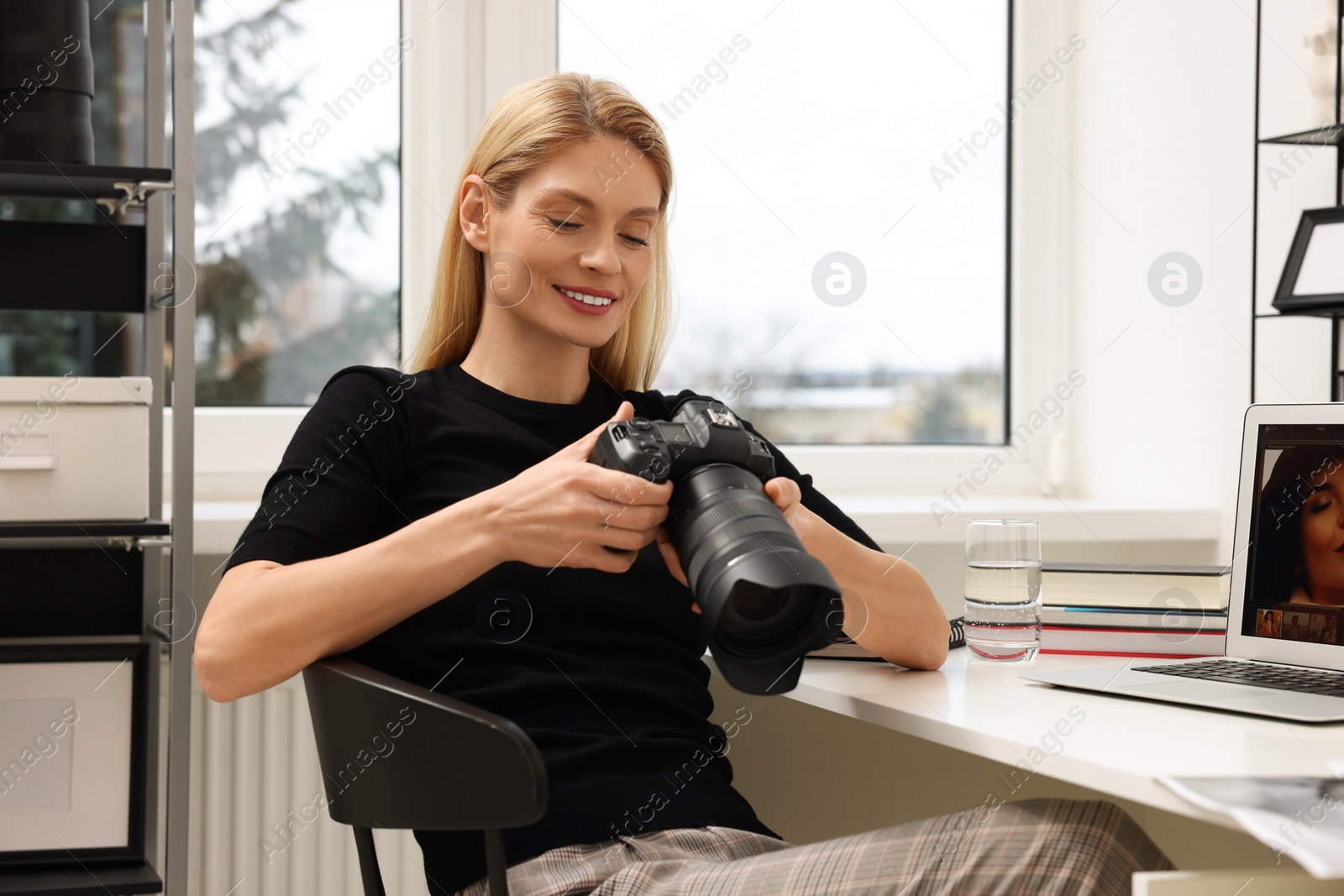 Photo of Professional photographer with digital camera at table in office