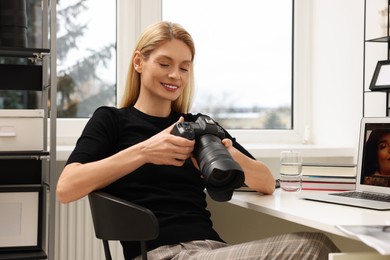 Professional photographer with digital camera at table in office