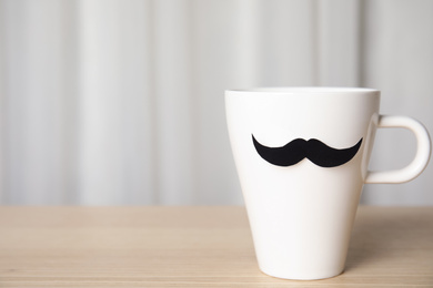 Photo of Cup with paper mustache on wooden table, space for text. Happy Father's day