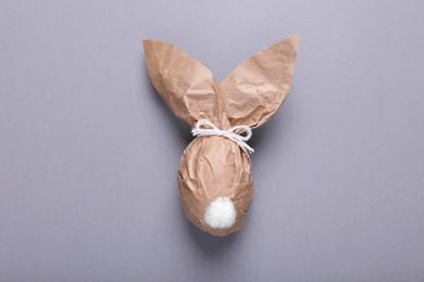 Photo of Easter bunny made of kraft paper and egg on grey background, top view