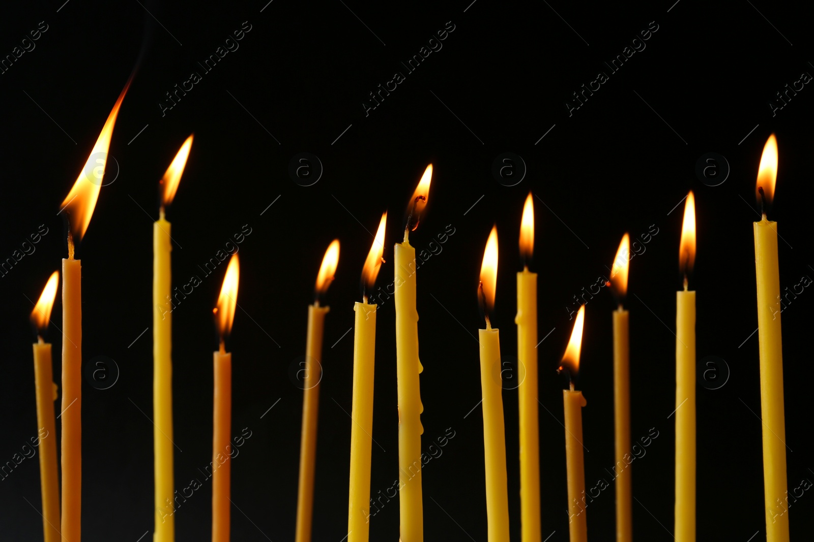 Photo of Burning candles on black background. Symbol of sorrow