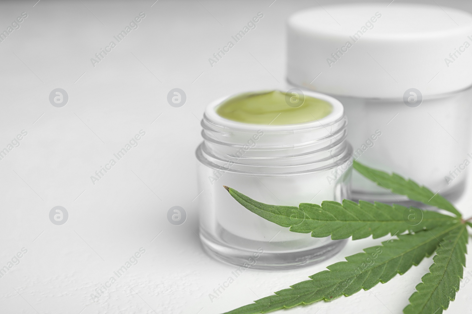 Photo of Jars of hemp cream on white table, space for text. Organic cosmetics