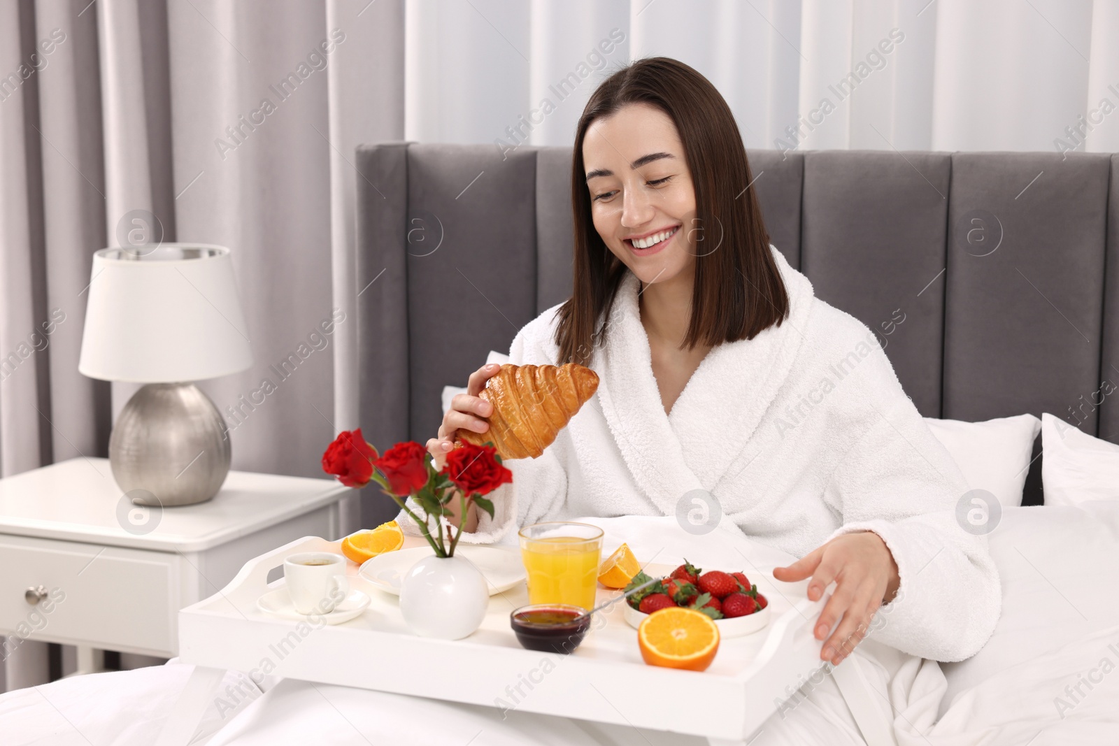 Photo of Smiling woman having breakfast in bed at home