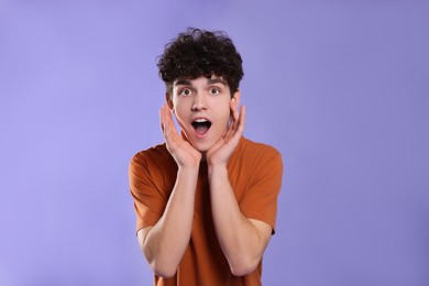 Portrait of shocked teenage boy on violet background