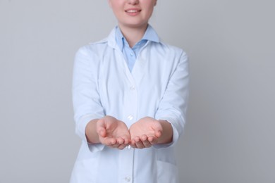 Photo of Dental assistant holding something on light grey background, closeup