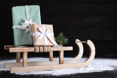Photo of Sleigh with gift boxes on black wooden table