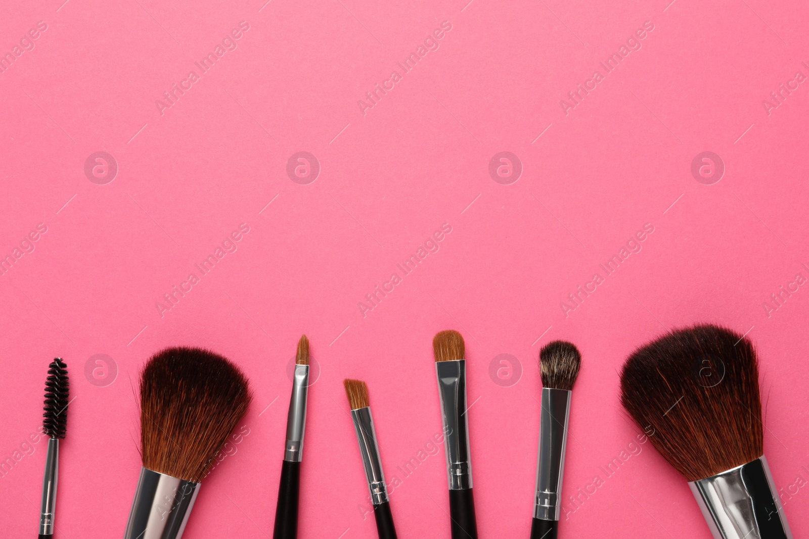 Photo of Set of makeup brushes on pink background, flat lay. Space for text