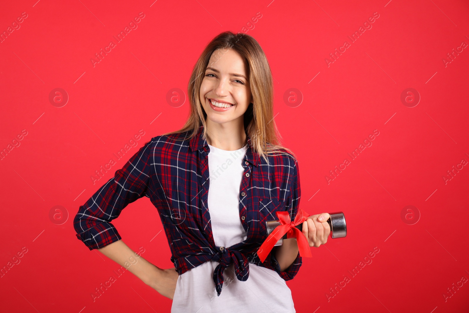 Photo of Woman with dumbbell as symbol of girl power on red background. 8 March concept