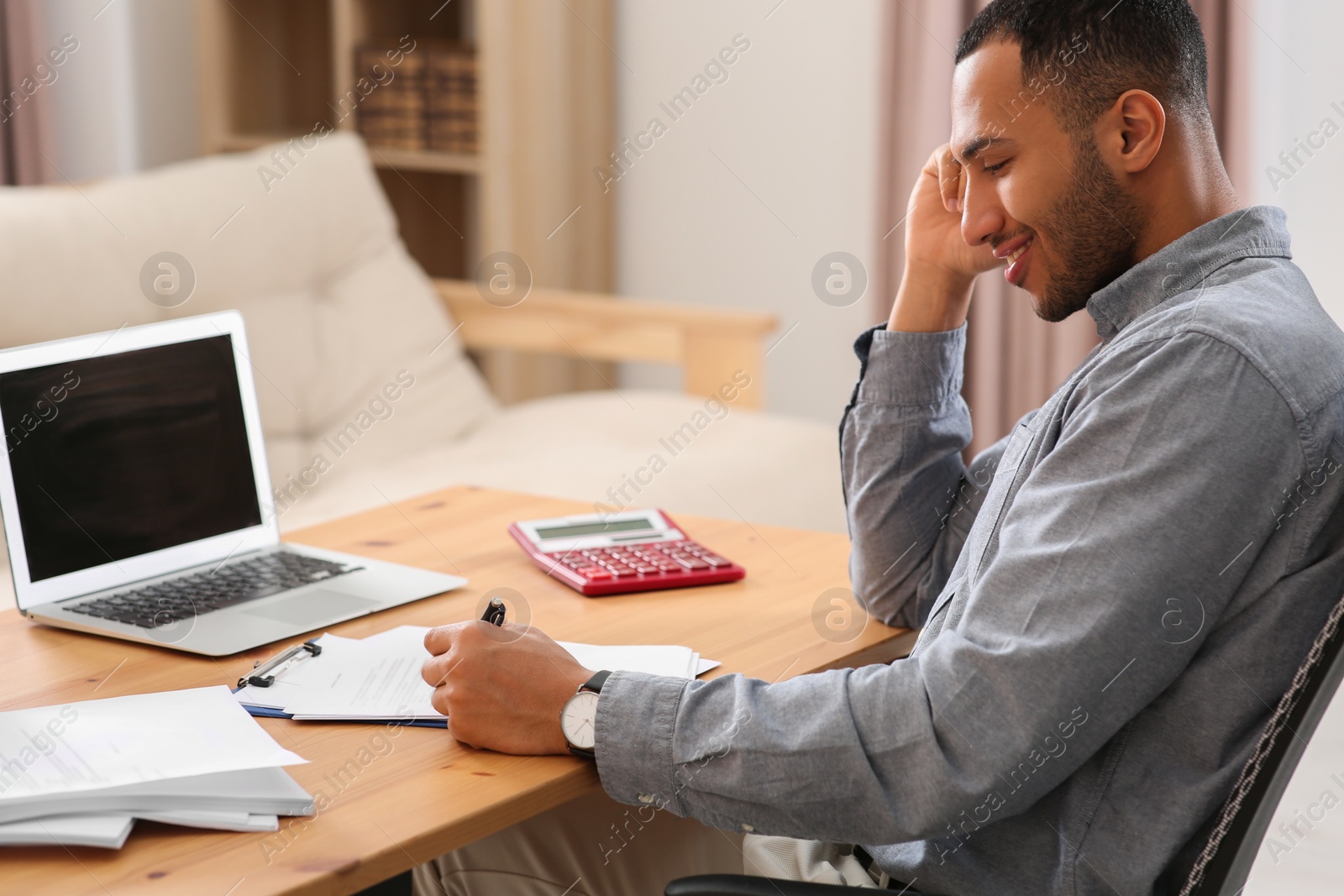 Photo of Happy businessman working with documents at wooden table in office