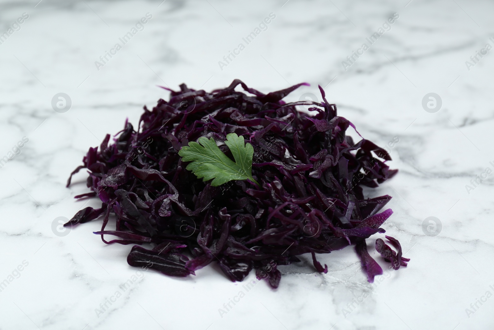 Photo of Tasty red cabbage sauerkraut with parsley on white marble table