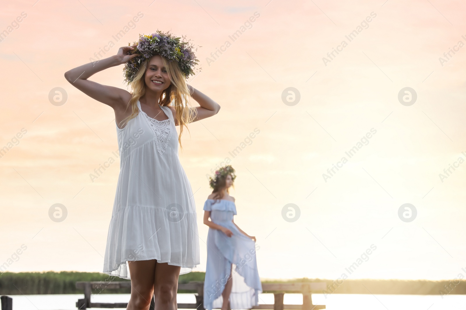 Photo of Young woman wearing wreath made of beautiful flowers near river