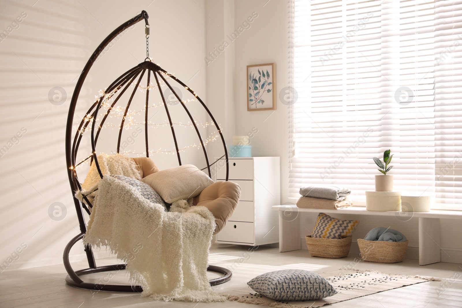 Photo of Cozy hanging chair with fairy lights in modern living room. Interior design