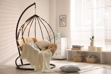 Photo of Cozy hanging chair with fairy lights in modern living room. Interior design