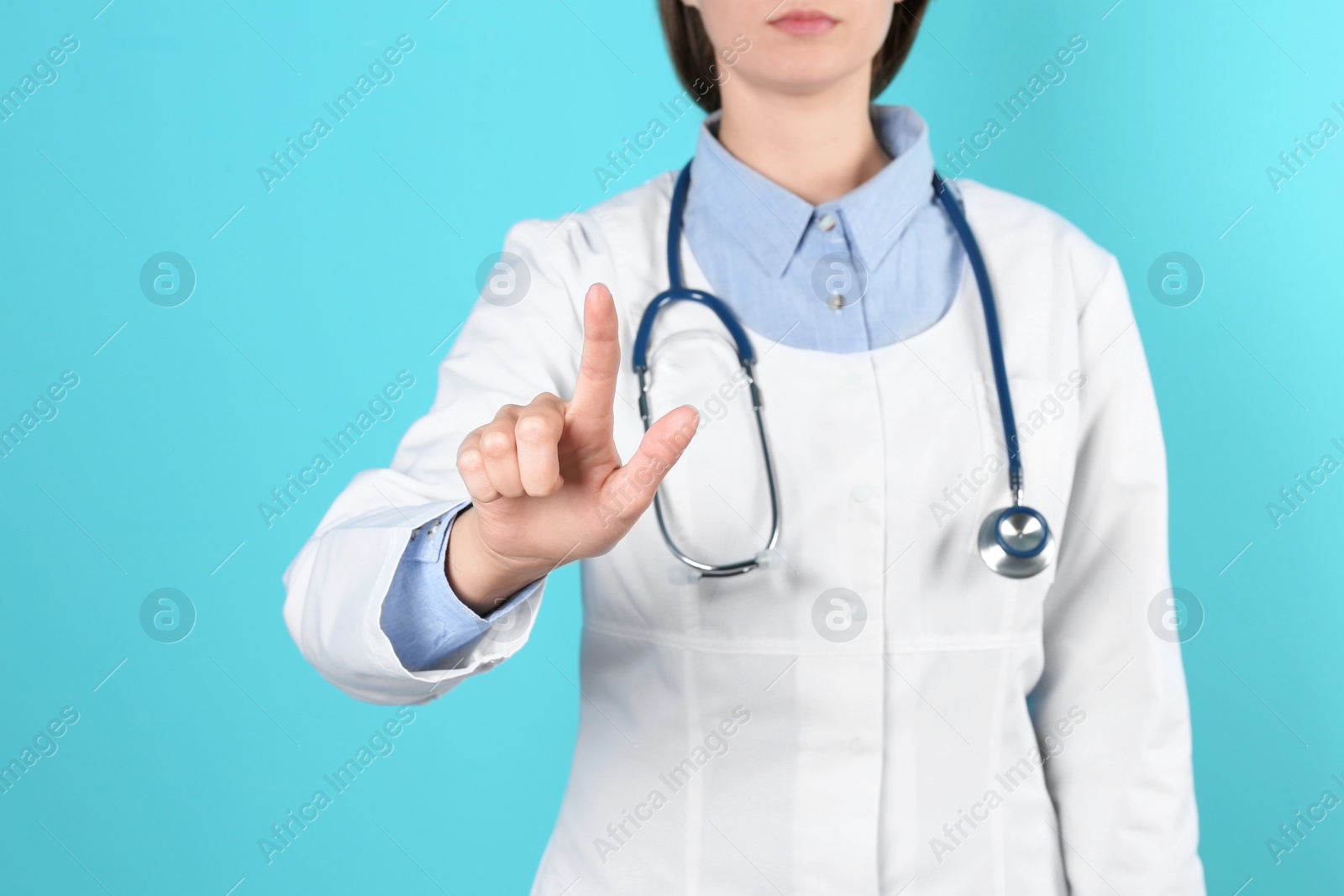 Photo of Female doctor pointing on color background, closeup