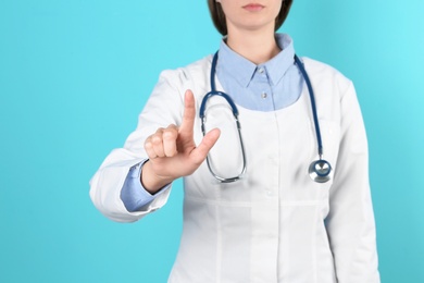 Female doctor pointing on color background, closeup