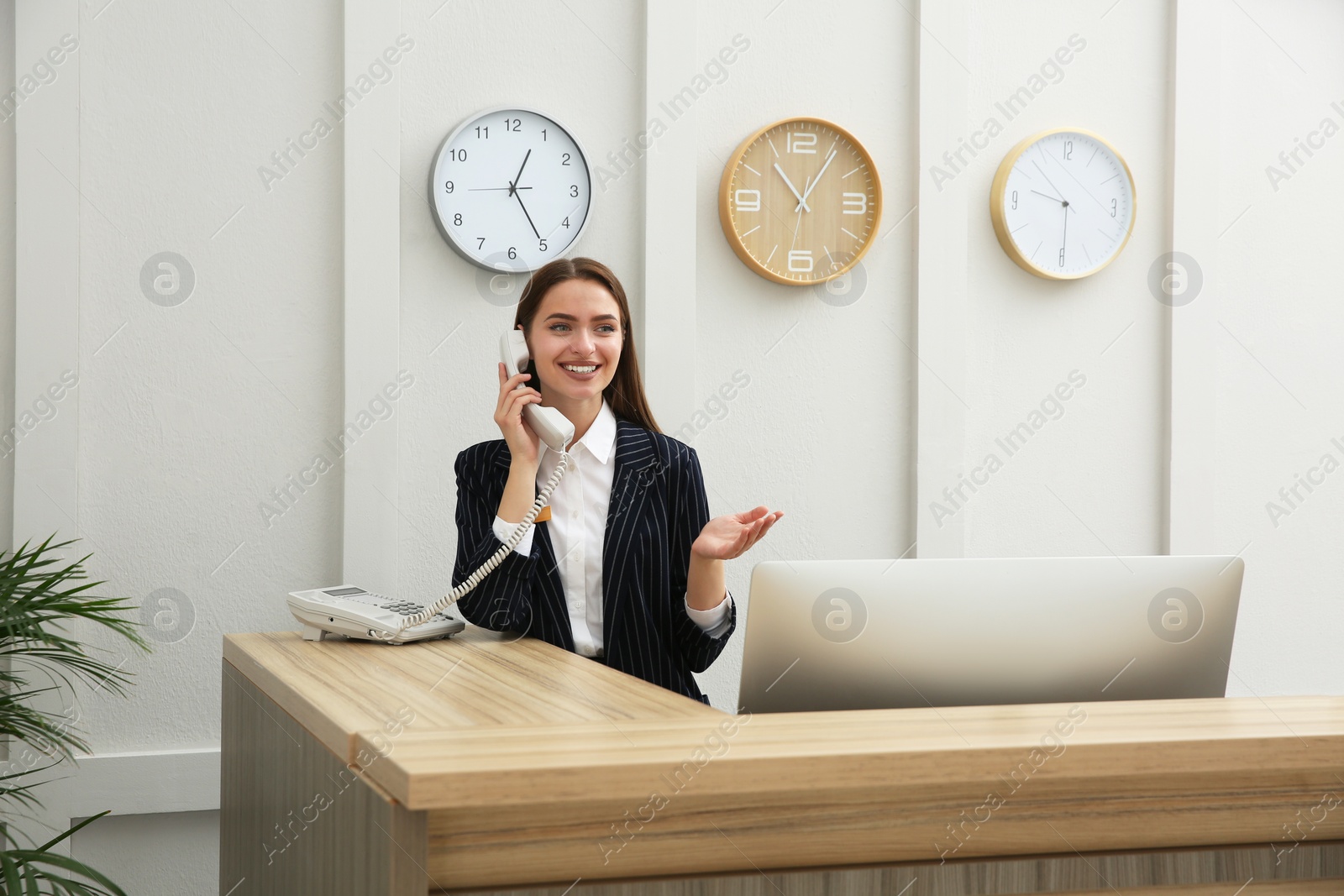 Photo of Beautiful receptionist talking on phone at counter in hotel