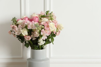 Beautiful bouquet of fresh flowers in vase near white wall, space for text