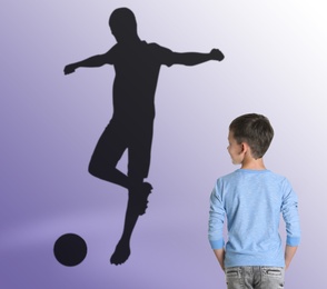 Image of Little boy dreaming to be soccer player. Silhouette of man behind kid