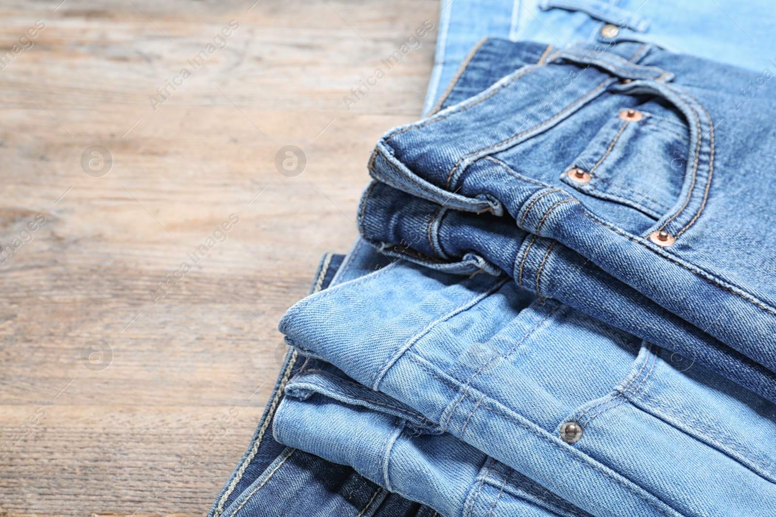 Photo of Collection of stylish jeans on wooden background, closeup. Space for text