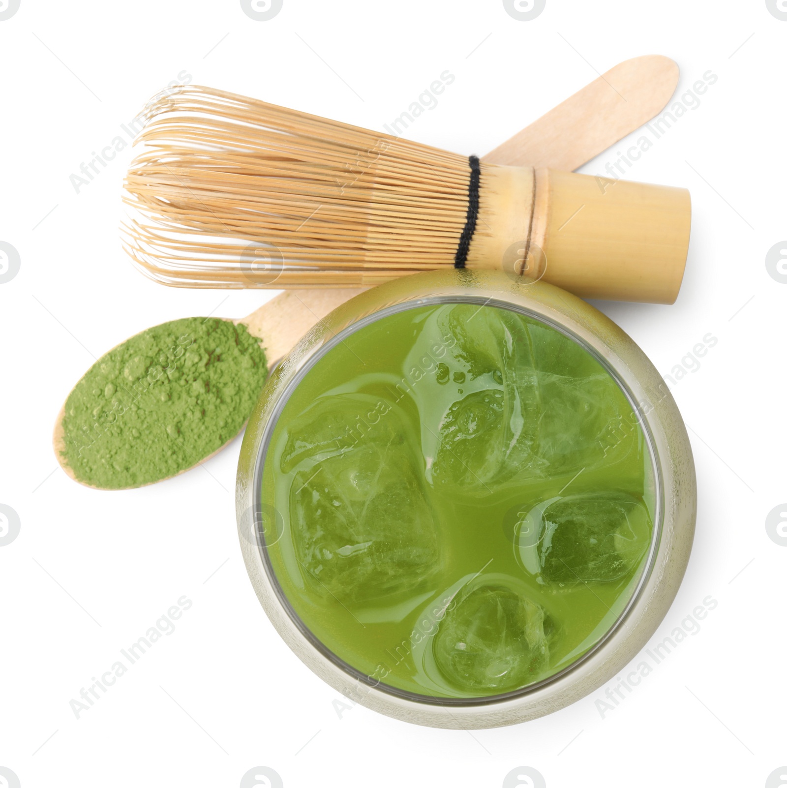 Photo of Glass of delicious iced green matcha tea, spoon with powder and bamboo whisk isolated on white, top view