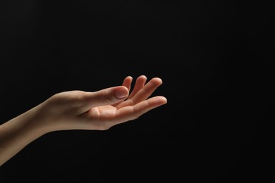 Photo of Woman holding something in hand on black background, closeup. Space for text