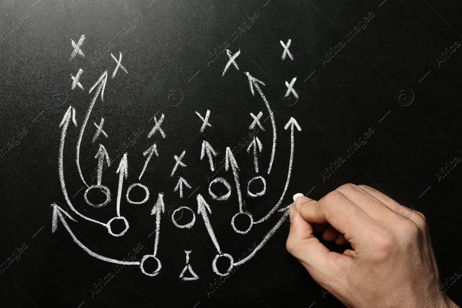 Photo of Man drawing football game scheme on chalkboard, top view