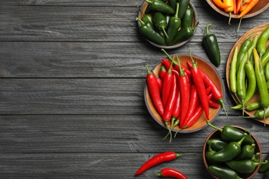 Photo of Different ripe chili peppers on grey wooden table, flat lay. Space for text