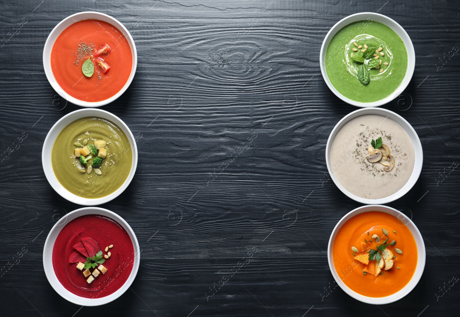 Photo of Various soups in bowls and space for text on wooden background, top view. Healthy food