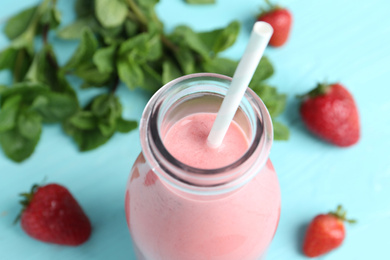 Photo of Tasty strawberry smoothie in bottle on table, closeup